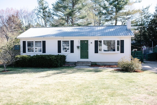 view of front of house with a chimney, a front yard, and metal roof