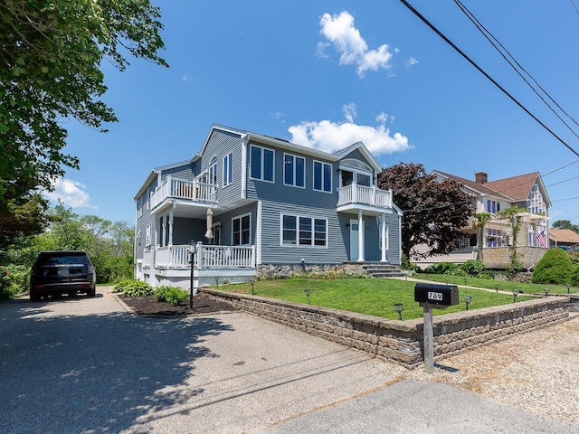view of front of house featuring a balcony and a front yard
