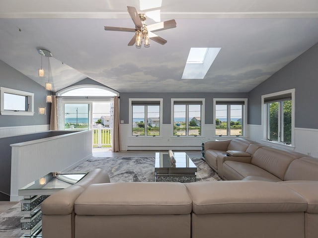 living room with vaulted ceiling with skylight, a ceiling fan, wainscoting, and wood finished floors
