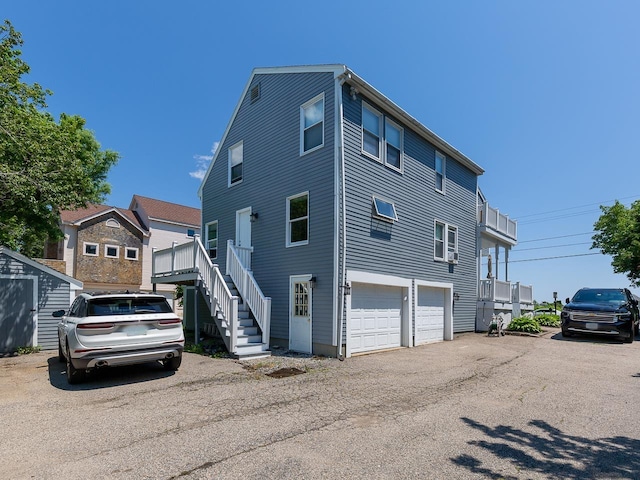 view of side of property featuring a storage shed, an attached garage, and stairs