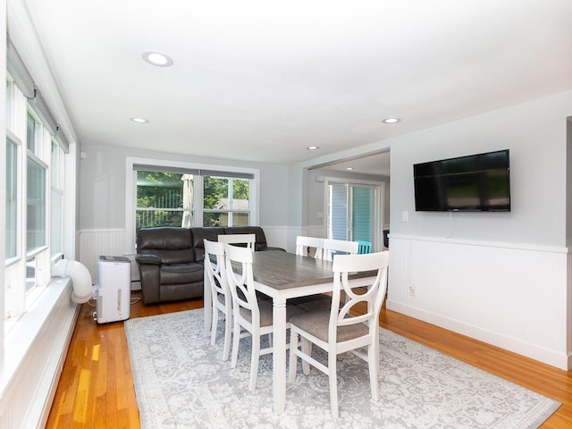 dining room with a wainscoted wall and light wood-style flooring