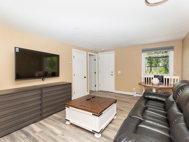living room with baseboards, a baseboard heating unit, and light wood-style floors