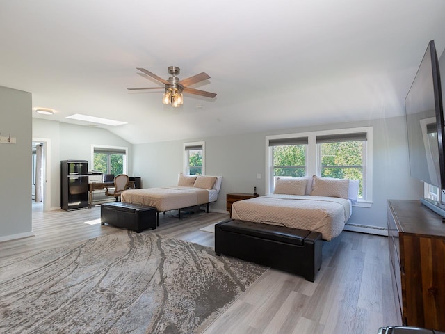 bedroom featuring vaulted ceiling with skylight, multiple windows, a baseboard heating unit, and wood finished floors