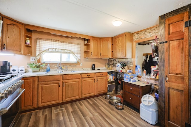 kitchen with open shelves, stainless steel range, a sink, light countertops, and wood finished floors