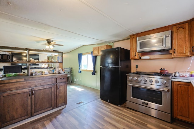 kitchen with a ceiling fan, visible vents, appliances with stainless steel finishes, wood finished floors, and lofted ceiling