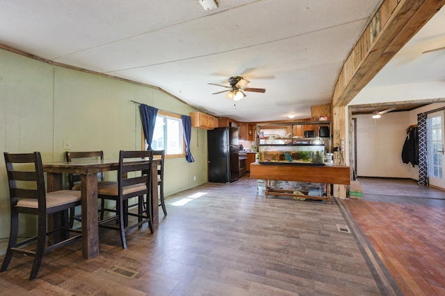 dining area with a ceiling fan, vaulted ceiling, wood finished floors, and visible vents