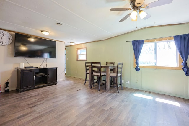 interior space with a ceiling fan, visible vents, wood finished floors, baseboards, and lofted ceiling