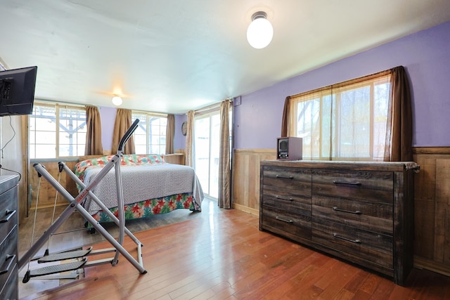 bedroom with a wainscoted wall and hardwood / wood-style floors
