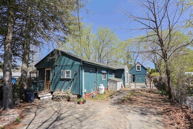 rustic home featuring fence and aphalt driveway