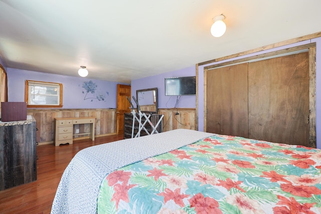 bedroom with wainscoting, wood finished floors, and wooden walls