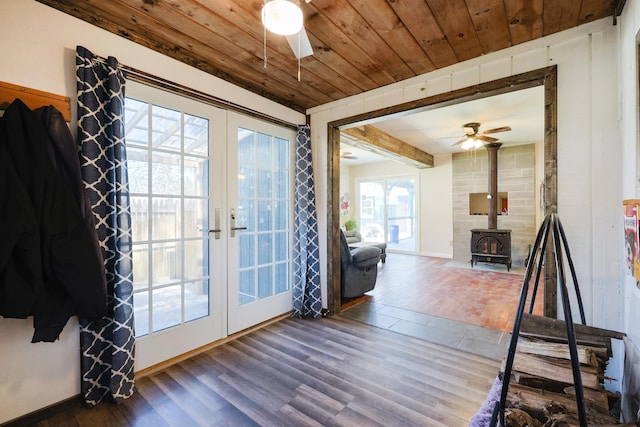 interior space with a ceiling fan, french doors, a wood stove, and wood ceiling