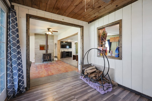 interior space featuring a wood stove, wood ceiling, ceiling fan, and wood finished floors