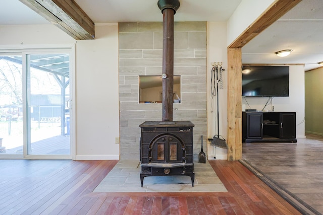 room details featuring baseboards, a wood stove, and wood finished floors