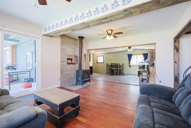 living area with a ceiling fan, baseboards, wood finished floors, and a wood stove