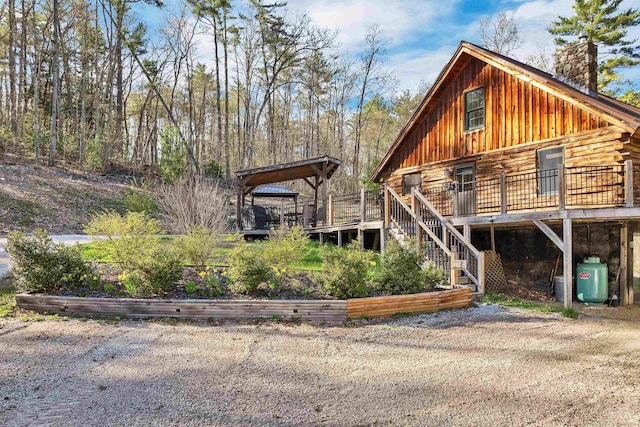 exterior space with a deck, a chimney, and stairway