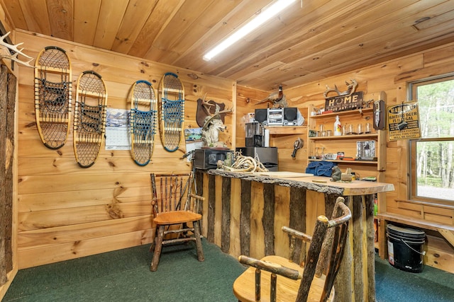 interior space with a bar, carpet flooring, wood ceiling, and wooden walls