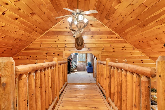 hall with wood walls, vaulted ceiling, wooden ceiling, and light wood-style floors
