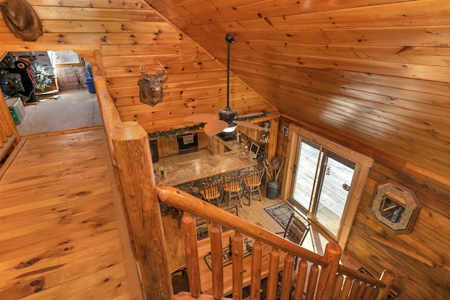 stairway with ceiling fan, wooden ceiling, wood-type flooring, lofted ceiling, and wooden walls