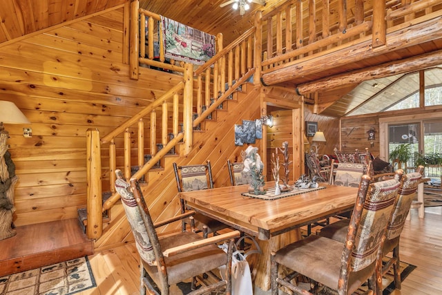 dining area with wood-type flooring, wood walls, lofted ceiling, stairway, and wood ceiling