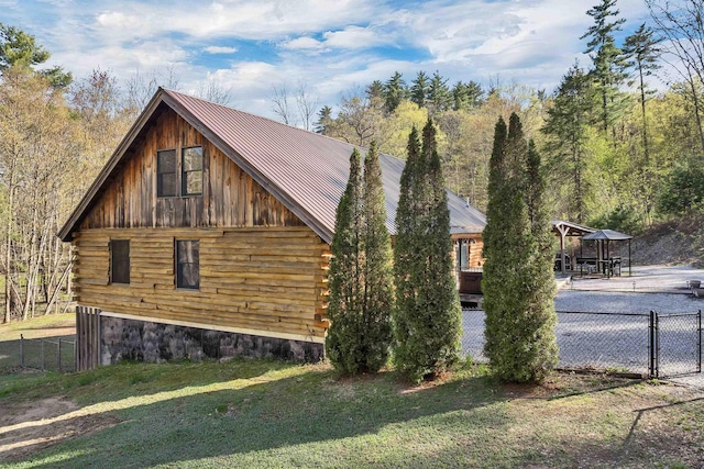 view of side of property featuring fence, a yard, a standing seam roof, and metal roof