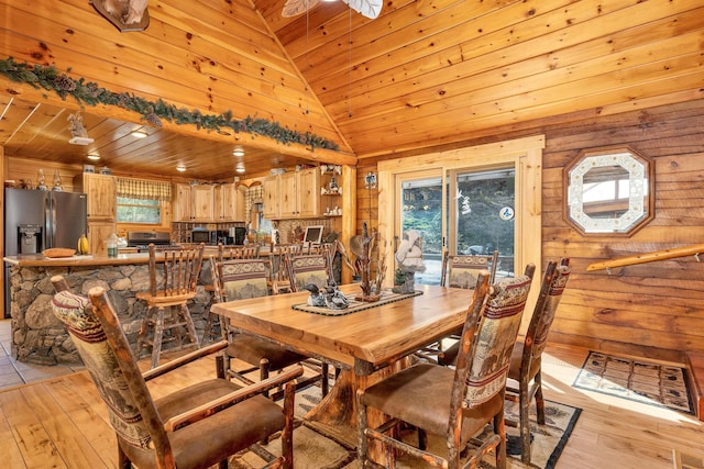 dining room with wooden walls, wooden ceiling, light wood finished floors, and lofted ceiling