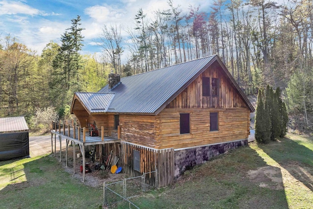 view of home's exterior with a deck, a chimney, a yard, and metal roof