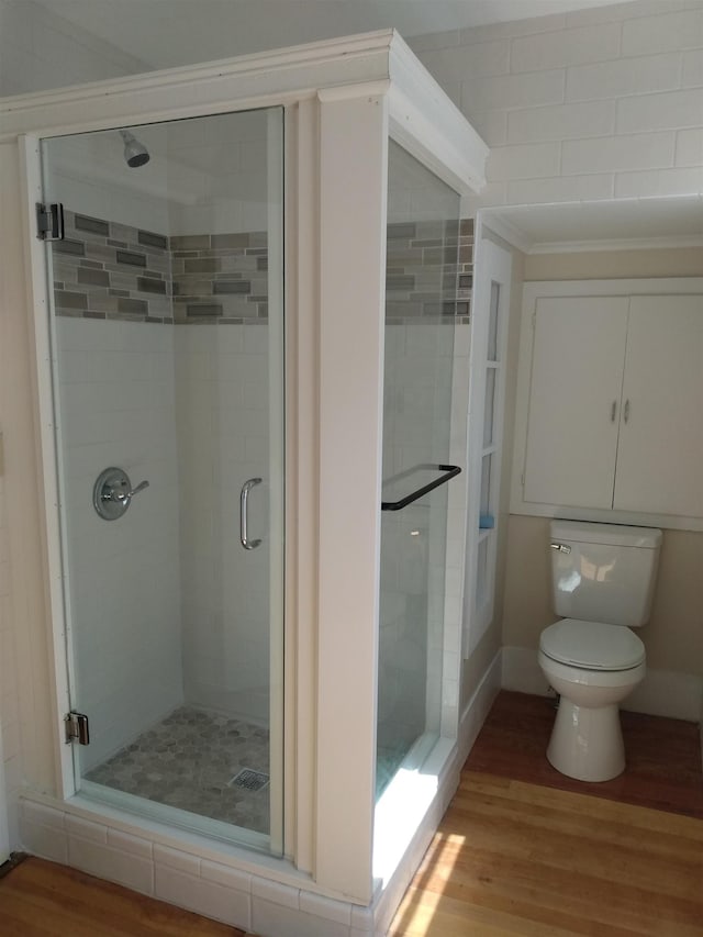 bathroom featuring wood finished floors, toilet, and a shower stall