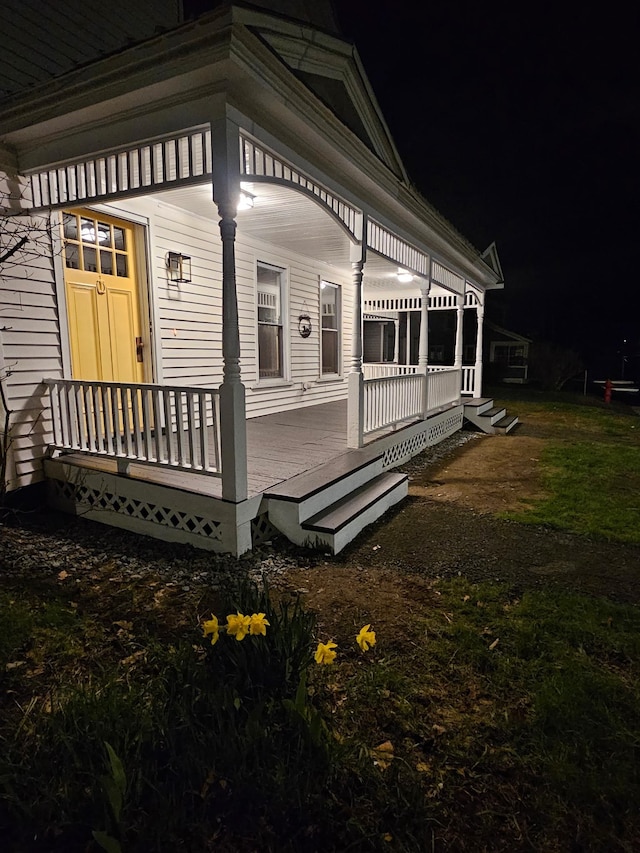 property exterior at night featuring covered porch