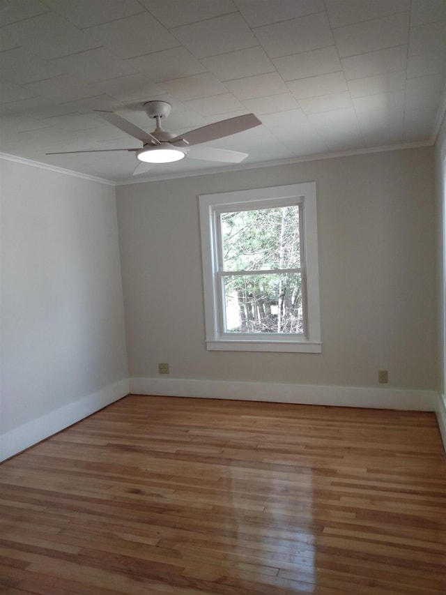 empty room with a ceiling fan, baseboards, ornamental molding, and wood finished floors