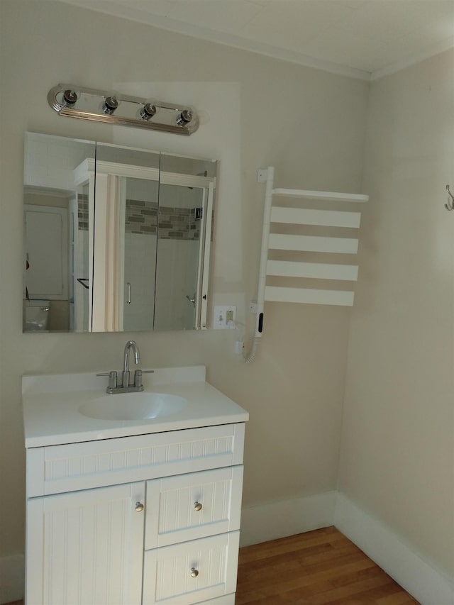 bathroom featuring vanity, baseboards, a shower stall, and wood finished floors