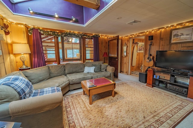 carpeted living area with wooden walls and visible vents