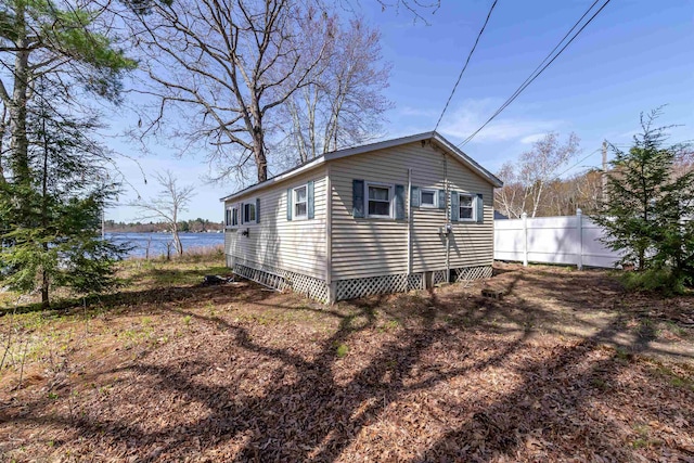 view of home's exterior with fence and a water view