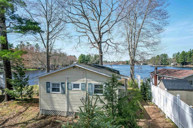 view of property exterior with a water view and fence