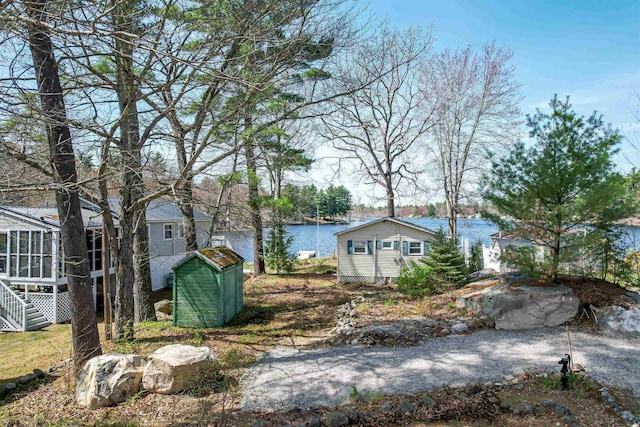 view of yard featuring a storage unit, a sunroom, stairway, a water view, and an outdoor structure