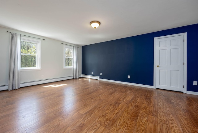 unfurnished room featuring baseboards, a baseboard radiator, and wood finished floors