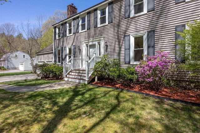 colonial home featuring a front lawn and a chimney