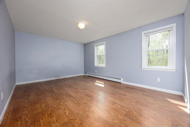 unfurnished room featuring baseboards, baseboard heating, and wood finished floors