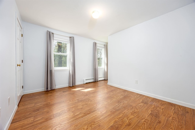 unfurnished room featuring baseboards, baseboard heating, and light wood-style flooring