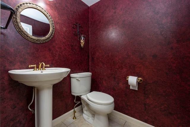 bathroom featuring toilet, baseboards, and tile patterned flooring