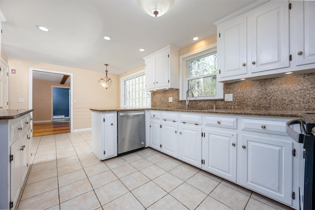 kitchen featuring stainless steel dishwasher, decorative backsplash, white cabinets, a sink, and dark stone countertops