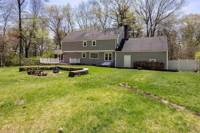rear view of property featuring a lawn, a deck, fence, and a chimney