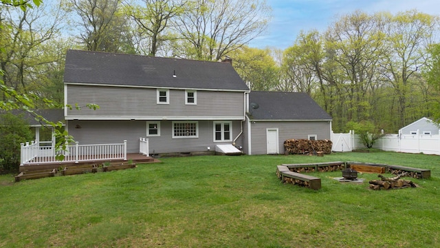 back of house with a fire pit, a wooden deck, fence, a chimney, and a yard