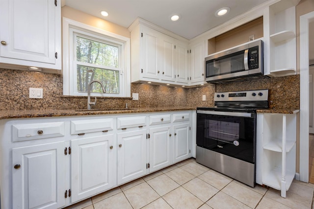 kitchen featuring open shelves, white cabinets, a sink, dark stone countertops, and appliances with stainless steel finishes