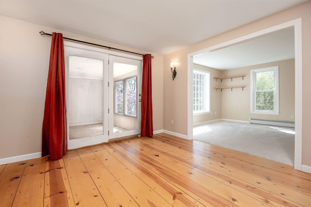 spare room with light wood-style floors, baseboards, and a baseboard radiator