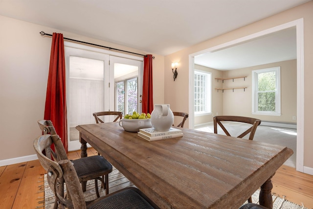 dining area featuring baseboards, a baseboard heating unit, and light wood-style flooring