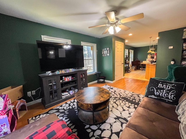 living room with light wood-style floors, baseboards, and ceiling fan
