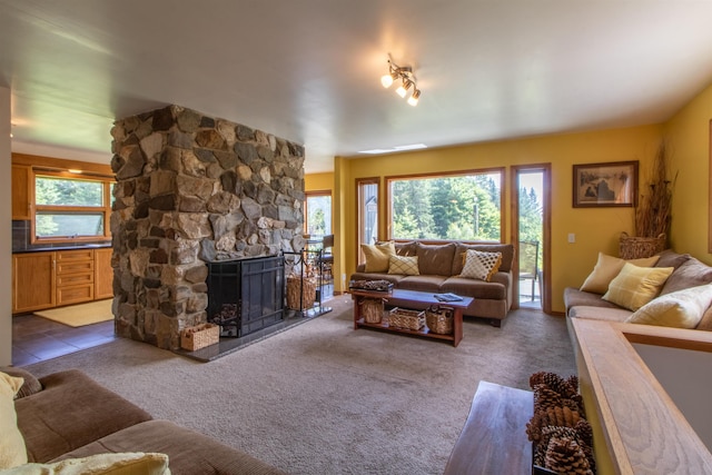 living area featuring dark carpet and a stone fireplace