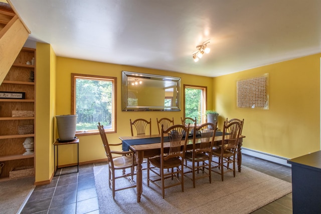 dining room featuring dark tile patterned floors, baseboards, and a baseboard heating unit