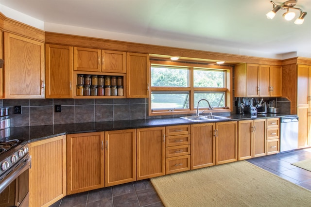 kitchen with brown cabinetry, a sink, appliances with stainless steel finishes, and dark tile patterned flooring