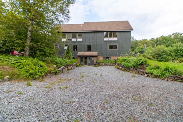 view of front of home with roof with shingles and gravel driveway